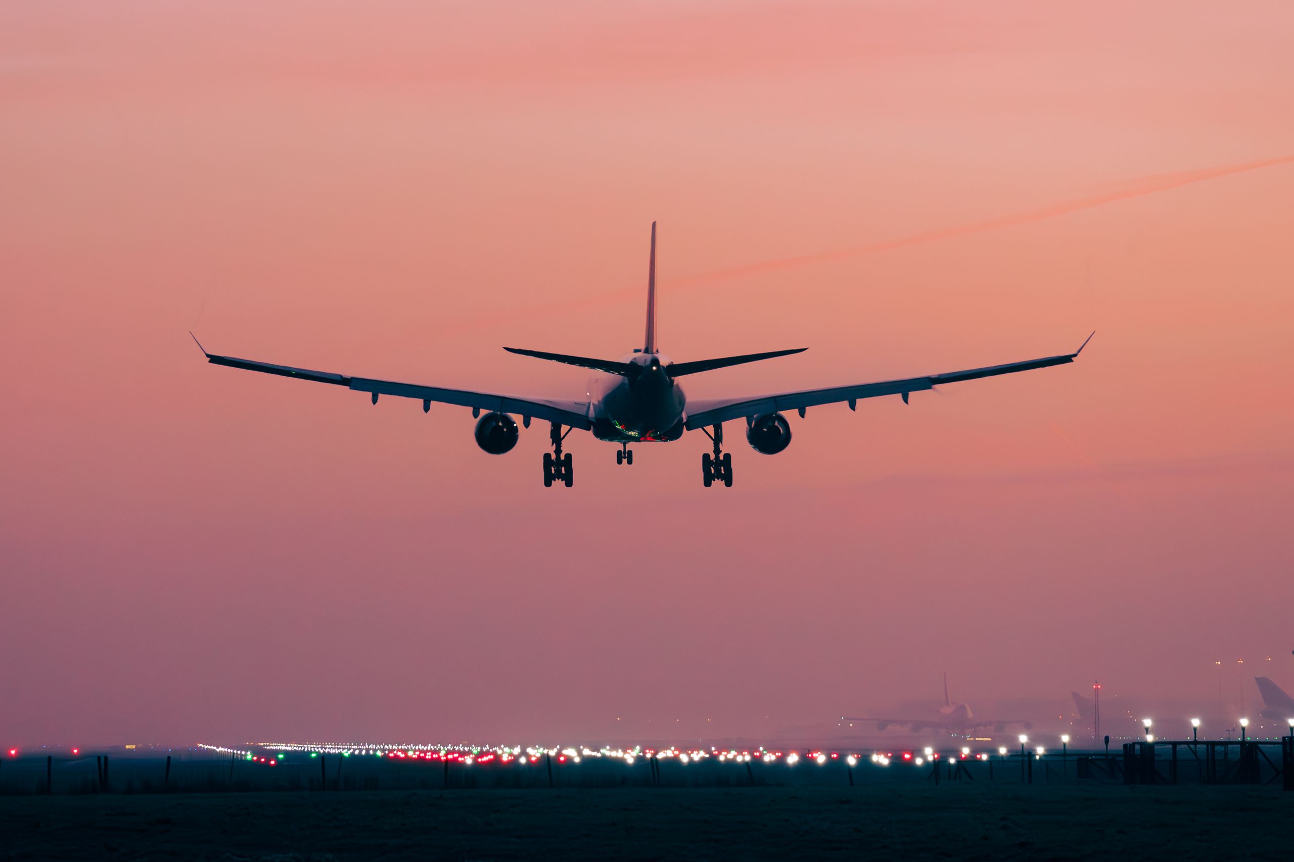 Airplane taking off at Schiphol Airport with a vibrant pink sunset sky. Perfect for travel themes.